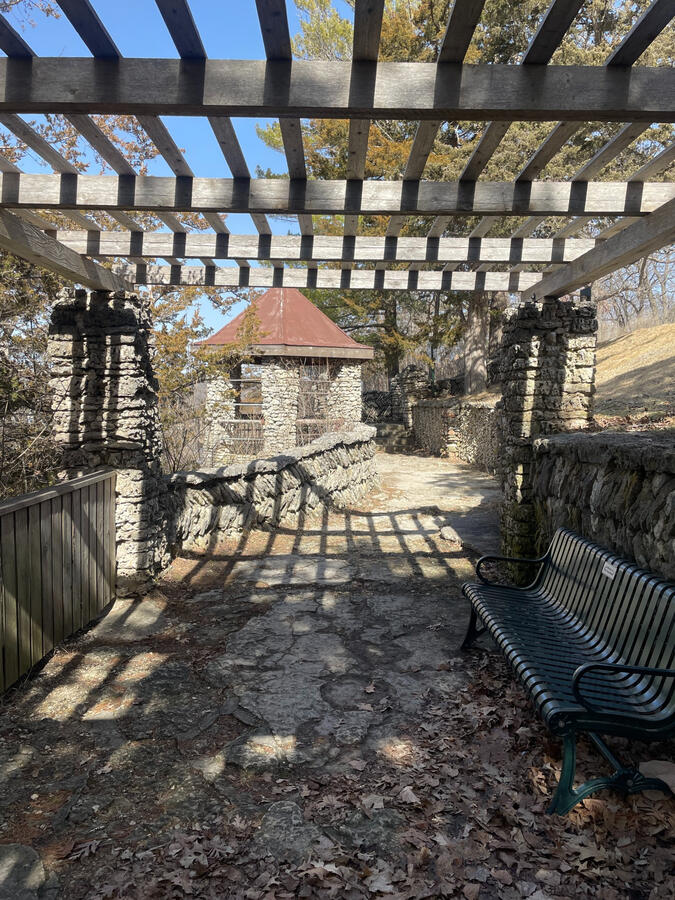 phelps-park-stone-pergola-decorah Stone pergola casting patterned shadows along a walkway in Phelps Park in Decorah.