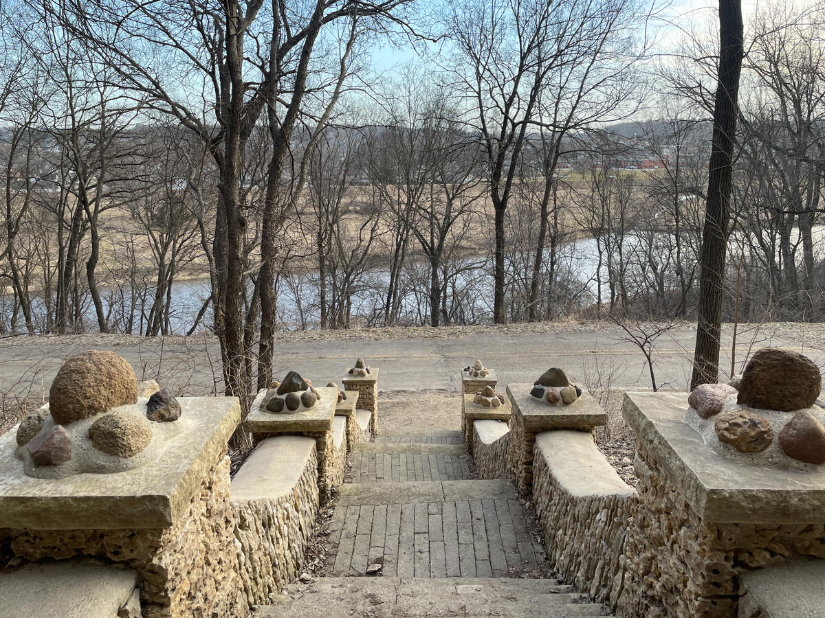 ice-cave-stair-overlook-river-road-decorah Stone stairway overlooking the road, trees, and river near the Ice Cave in Decorah.