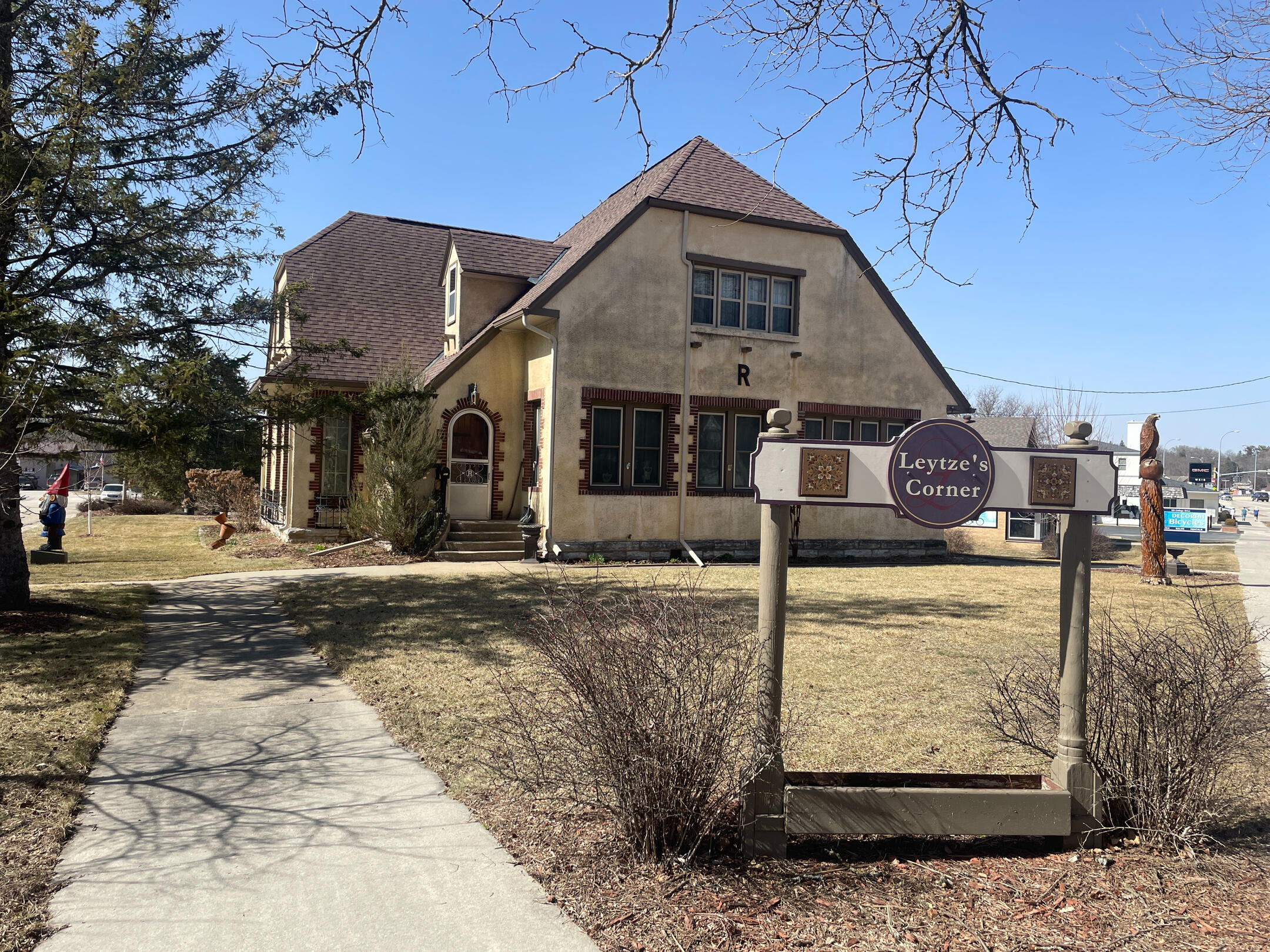 leytzes-corner-bed-and-bath-exterior-decorah Corner‑lot stucco building with brown trim and a front sign for Leytze’s Corner Bed and Bath in Decorah.