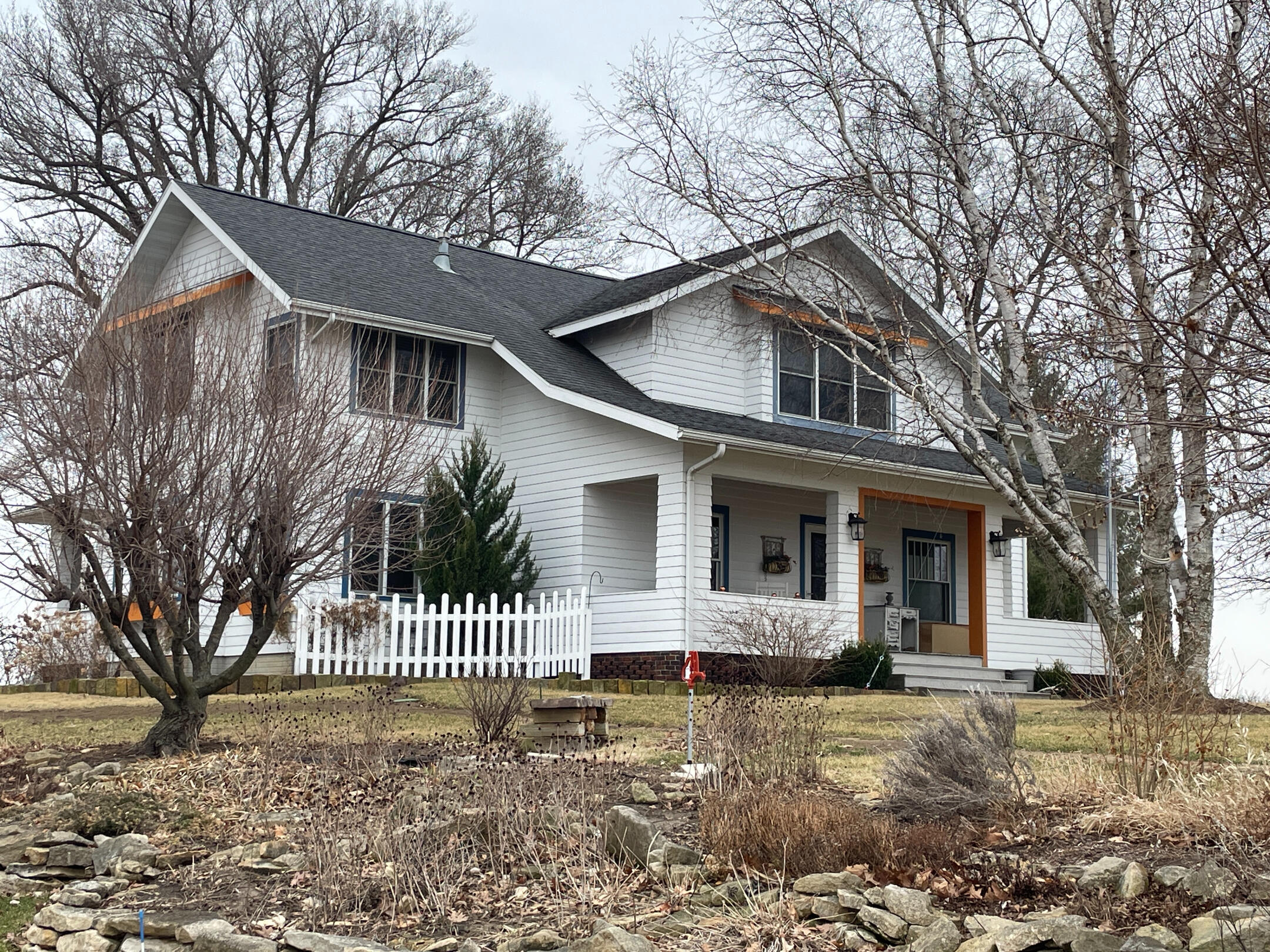 pella-cheesemakers-inn-historic-home-exterior White two‑story Cheesemaker’s Inn with covered porch, dark roof, and winter landscaping.